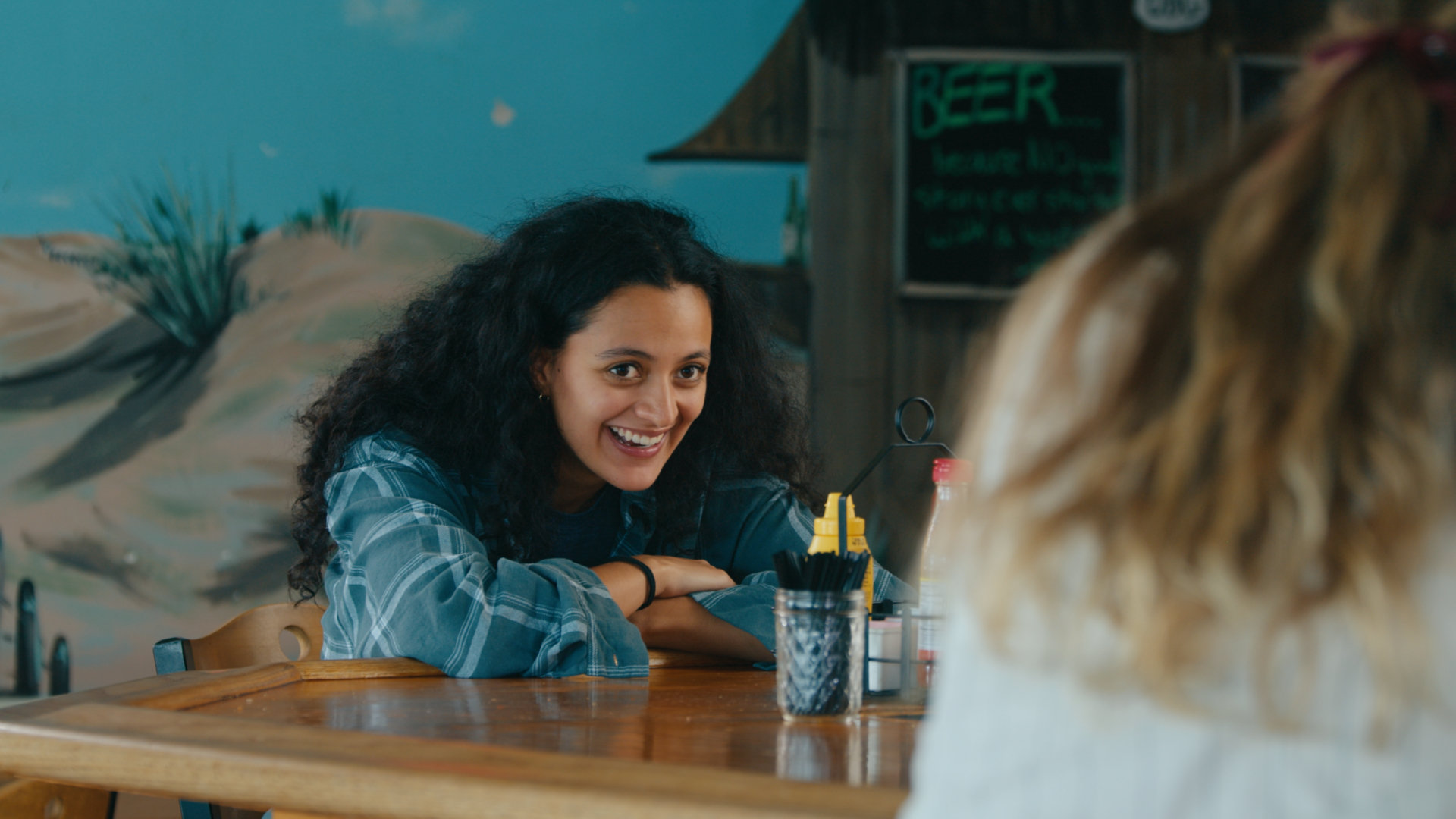 A smiling woman leaning across the bar in conversation