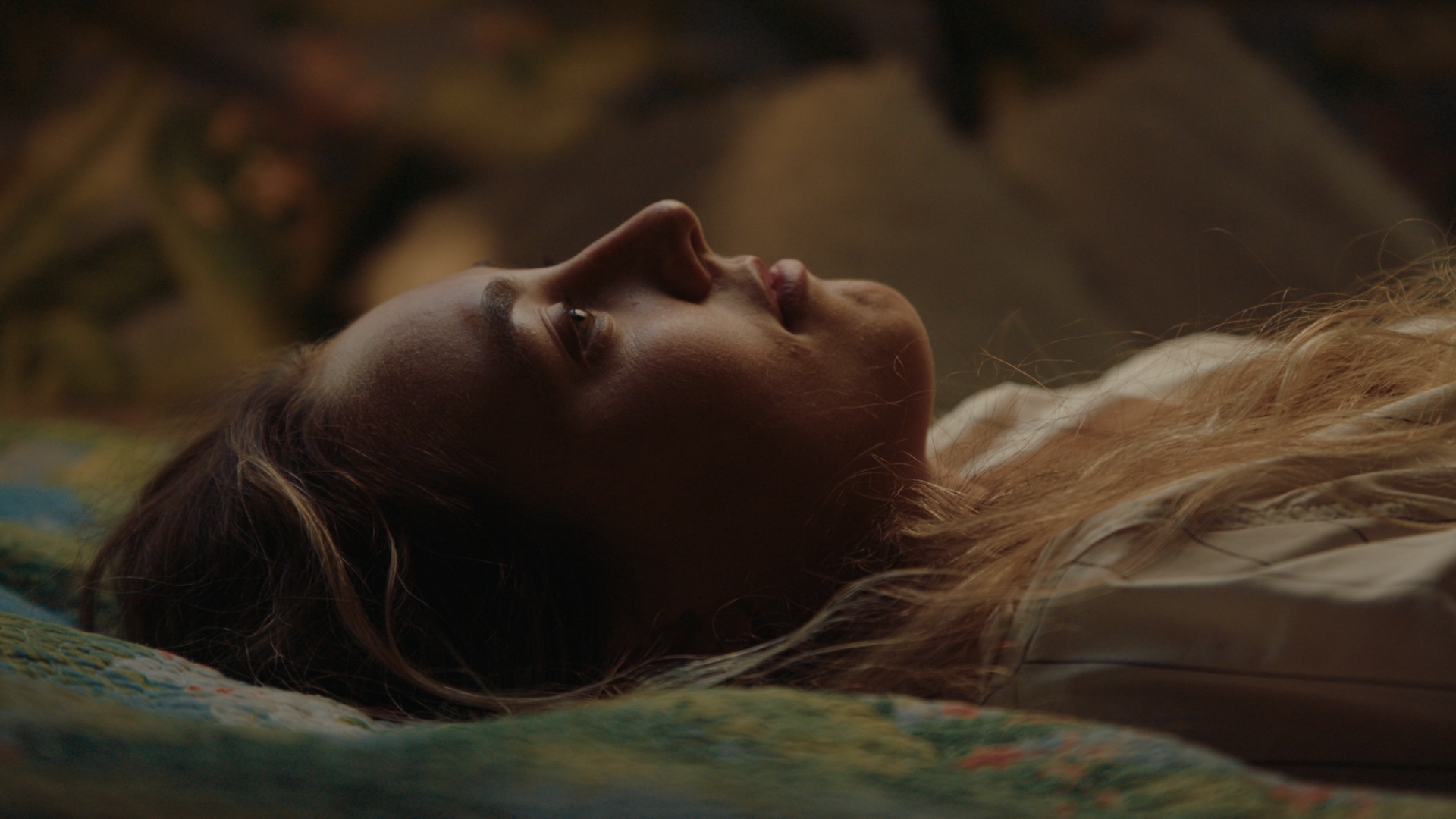 Close-up of a character resting, hair fanned across a quilt