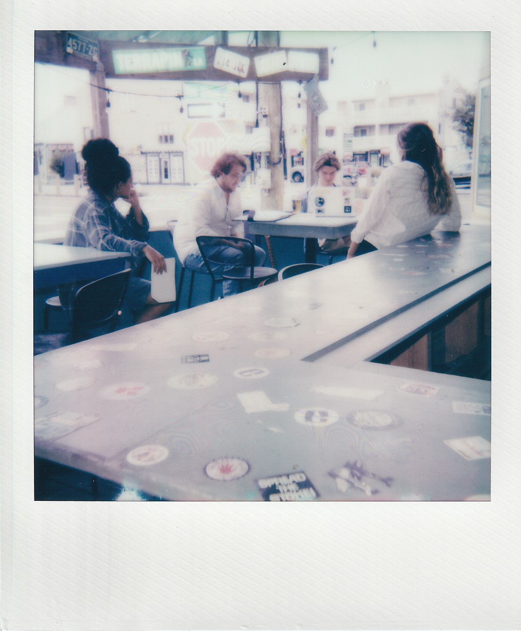 Polaroid of the Dewey Days director and cast at a sticker-covered bar.